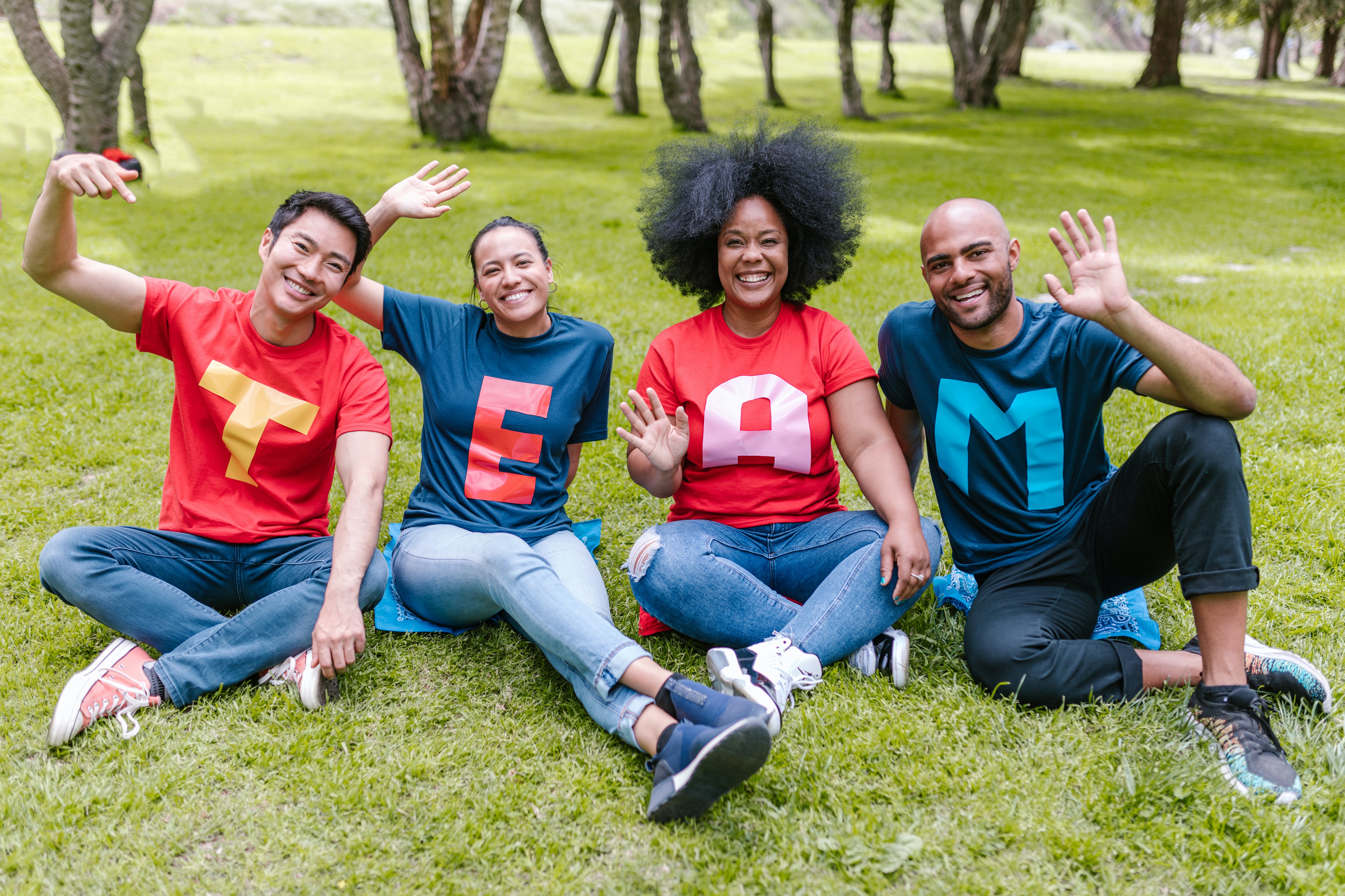 A group of people sitting on the grass and waving